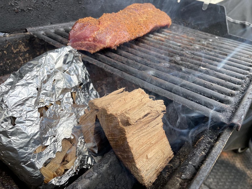 gas grill setup for smoking with wood chips on one side and pork ribs on the cool zone