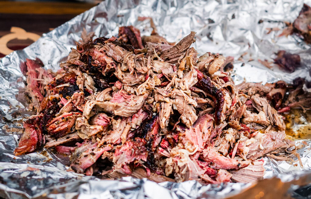 Smoked lamb shoulder pulled on foil with pink smoke ring and charred edges
