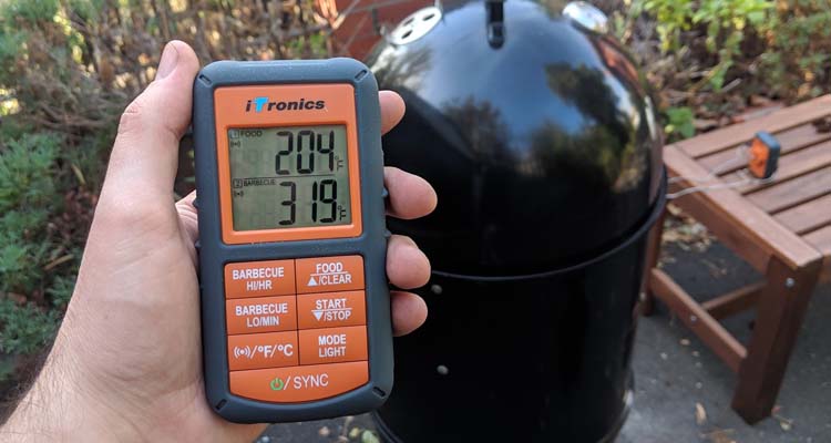 hand holding Thermopro tp 08 in front of smoker