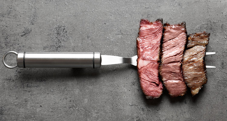 Steak cooked to different levels of doneness on a fork