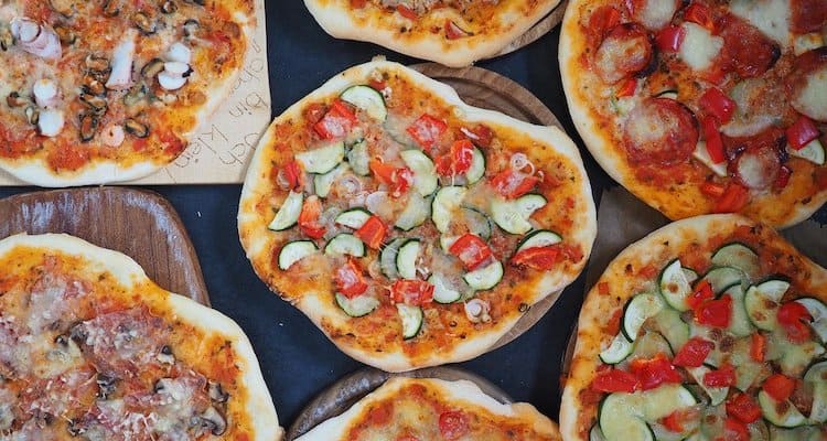 different types of pizza on wooden boards