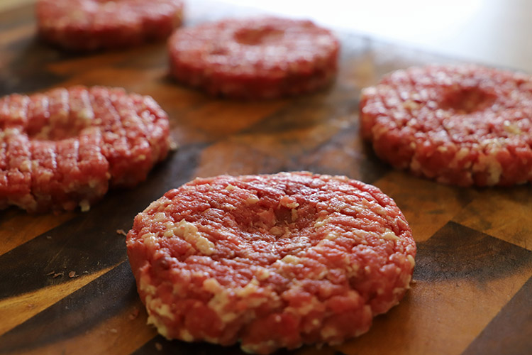 uncooked burger patties on a wooden board