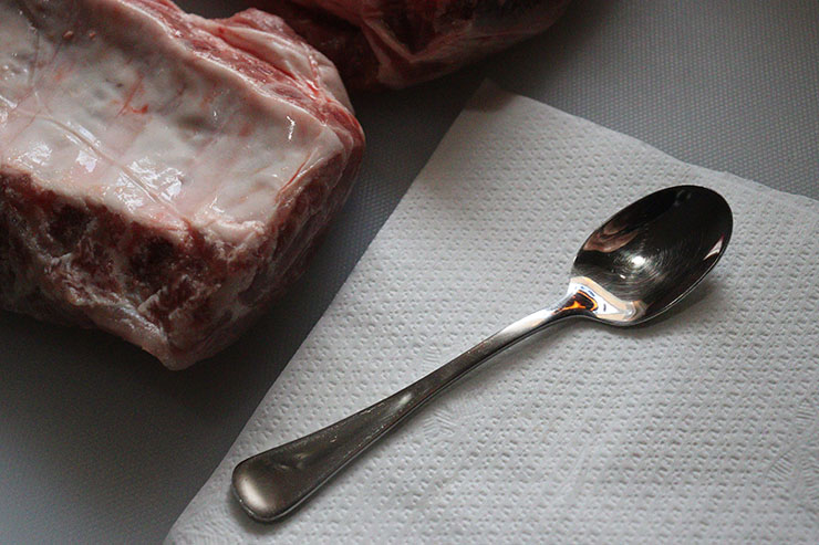 a metal teaspoon on a piece of paper towel and pork baby back ribs