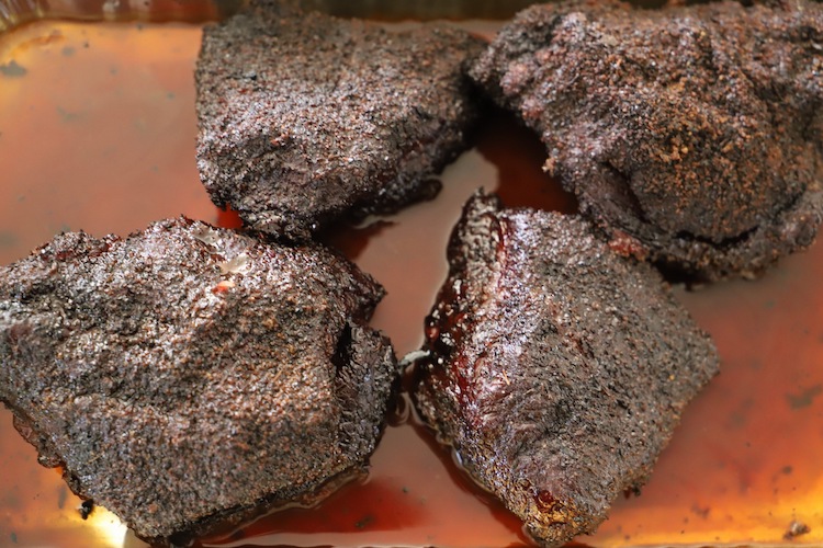 smoked beef cheeks in a tray with liquid
