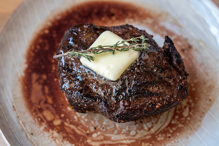 Grilled top sirloin steak with pat of butter and sprig of rosemary