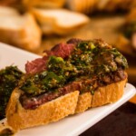grilled picanha steak on a piece of baguette topped with chimichurri sauce