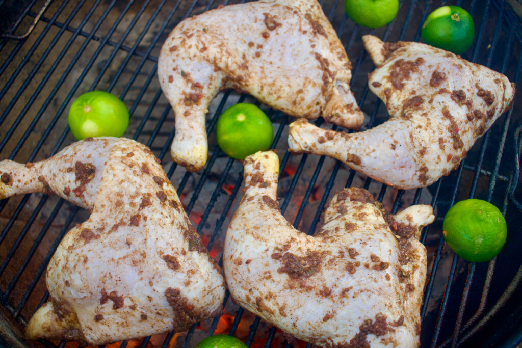 chicken quarters and lime halves on the grill