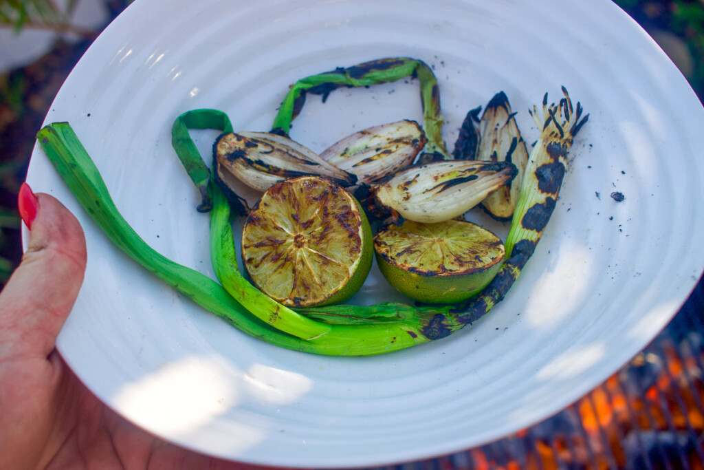a bowl of grilled green onions, lime, and shallots