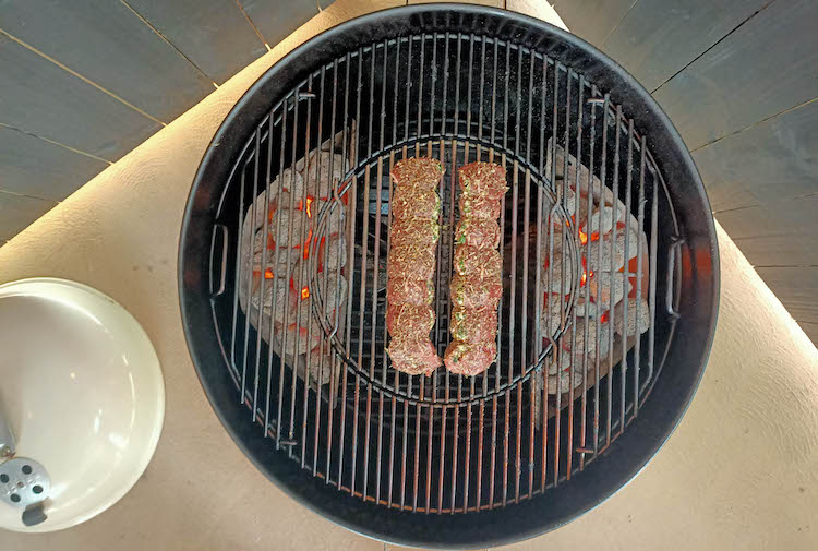 uncooked lamb backstraps on a weber kettle