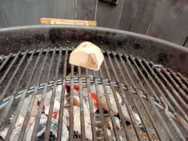 a piece of smoking wood placed over lit charcoal