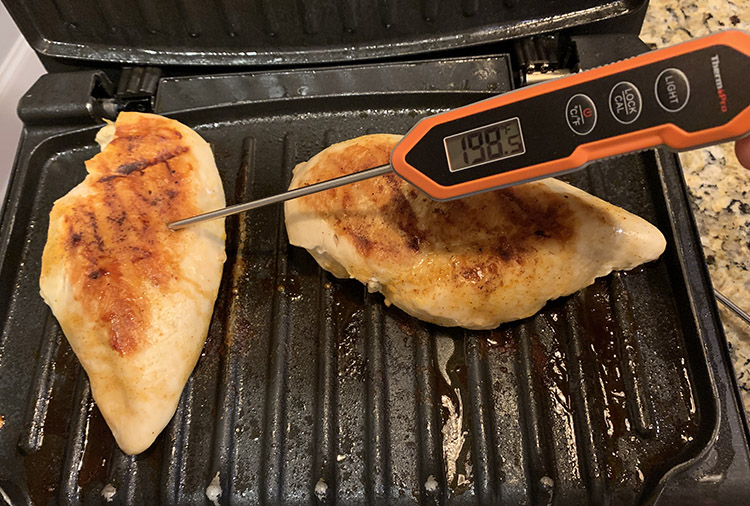 chicken breasts on a grill with ThermoPro TP15H digital instant read meat thermometer