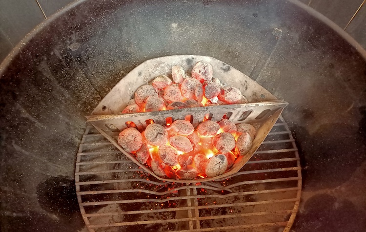 Lit charcoal briquettes inside the Weber Kettle charcoal grill