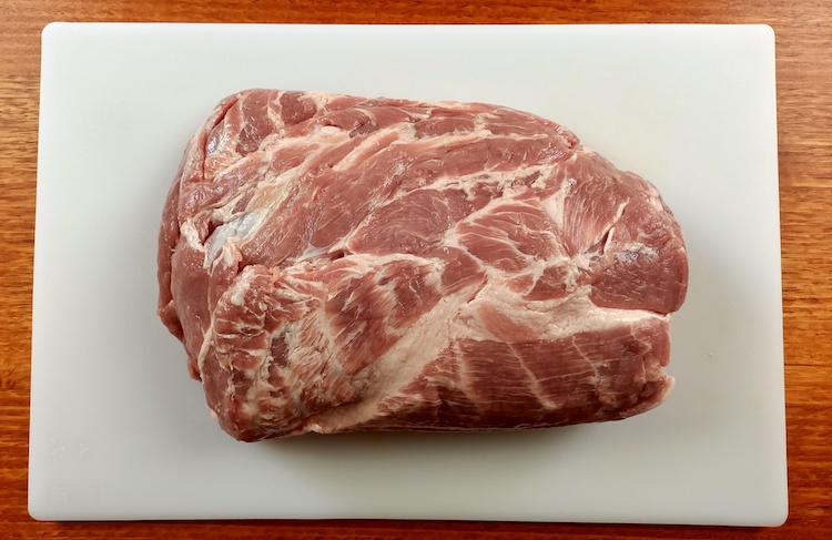 pork collar butt cut on a chopping board