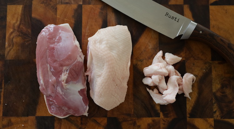 duck breasts with trimmed fat on a wooden board
