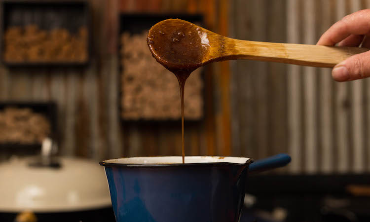 ham glaze on a spoon over a saucepan