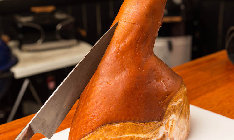 slicing the side of the ham with a knife