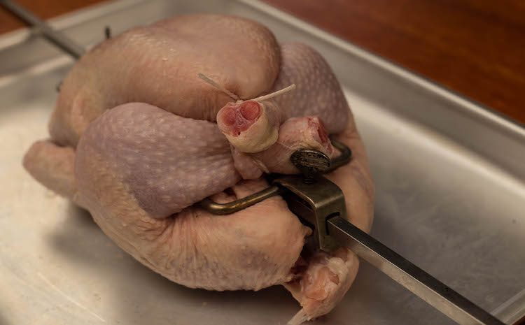 uncooked whole chicken on a rotisserie