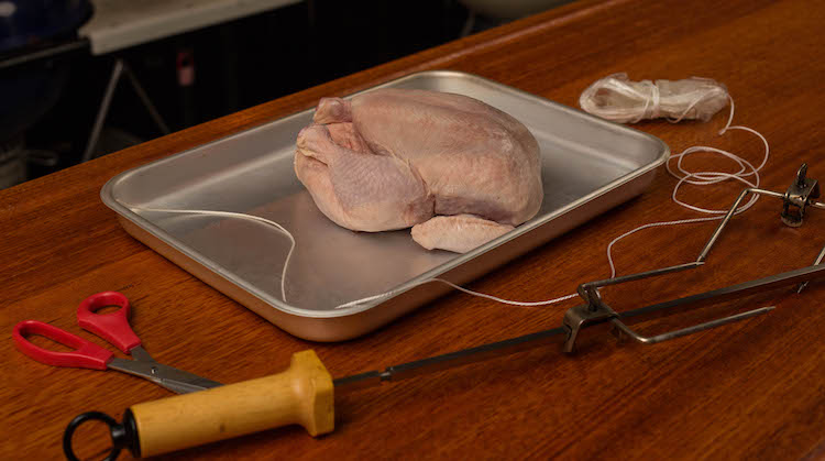 uncooked whole chicken on a metal tray