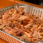 Smoked pulled pork in a foil tray topped with bbq sauce