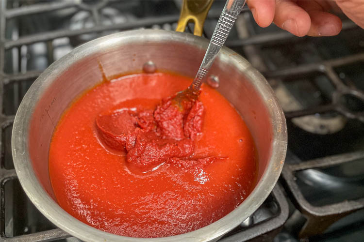 tomato sauce in a pot being stirred with silver spoon