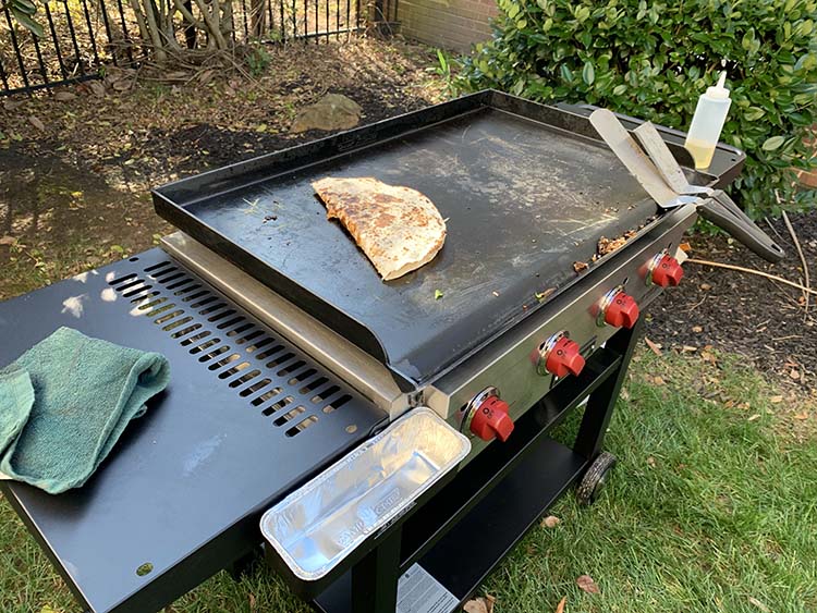 Camp Chef Flat Top Grill with side tables and food cooking on a griddle