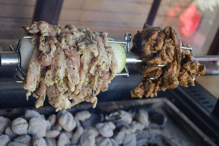 sliced chicken and lamb shoulder cooking a rotisserie rod