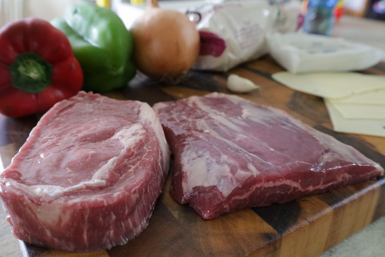 raw ribeye and flank steaks on a wooden board