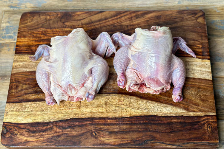 raw cornish hens on wooden chopping board
