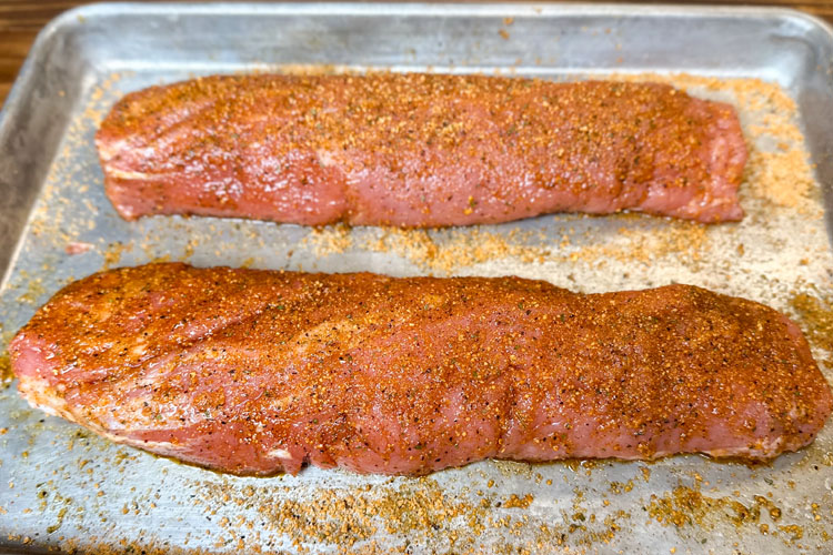 seasoned pork tenderloin on silver sheet tray