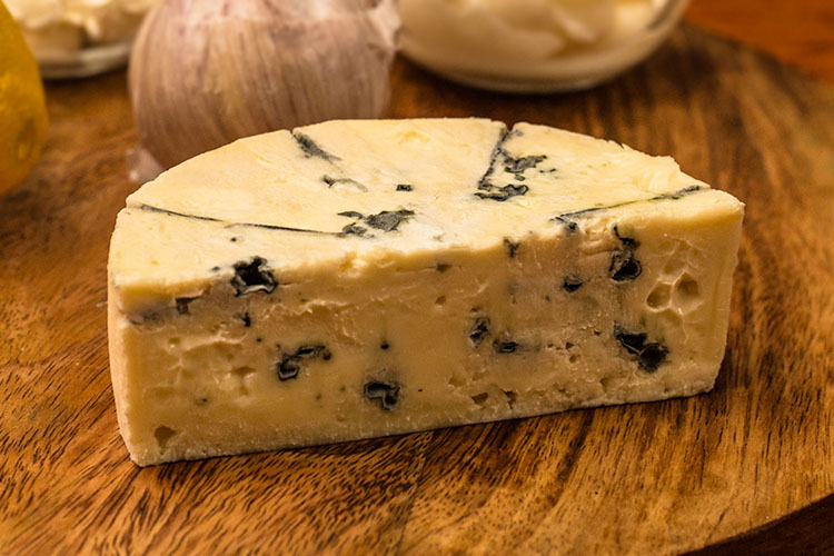 a piece of blue cheese on a wooden board