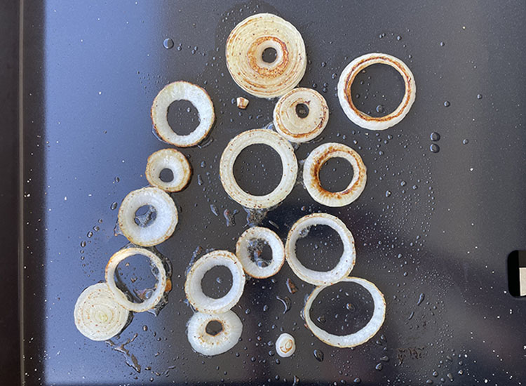 sliced onions cooking on a griddle