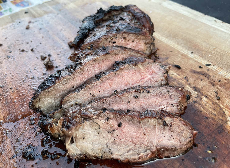sliced caveman ribeye steak on wooden board