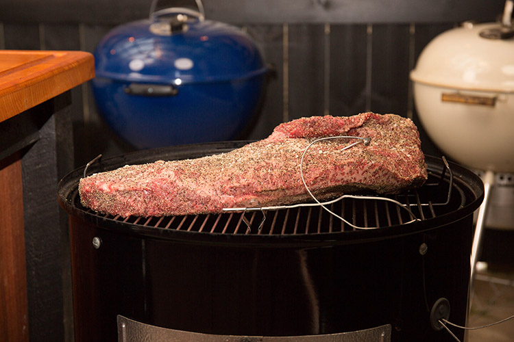uncooked beef brisket with temperature probes on a weber smokey mountain