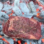 ribeye steak cooking directly on hot coals