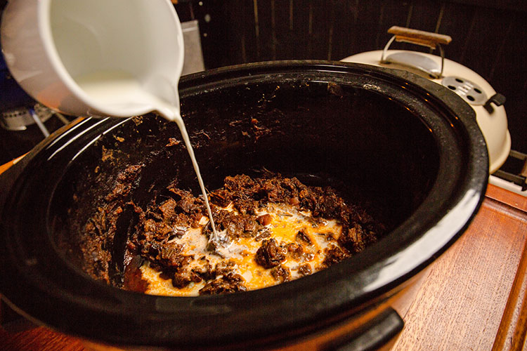 pouring milk into a Bolognese sauce
