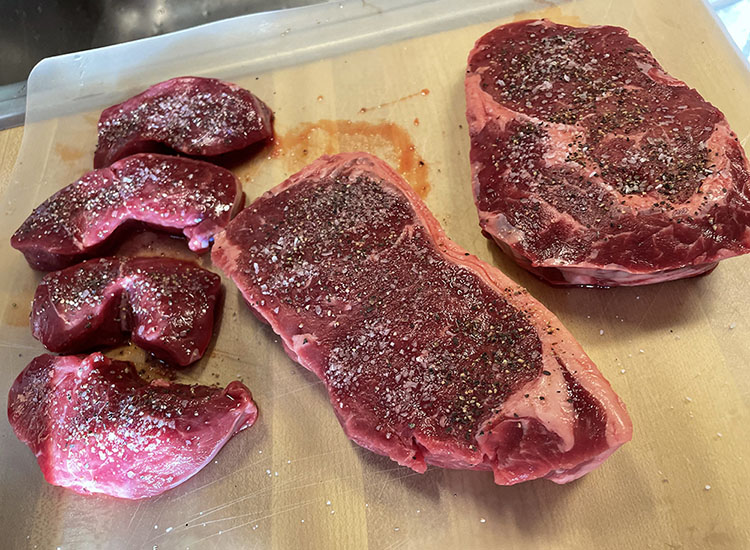 raw steaks on a wooden board