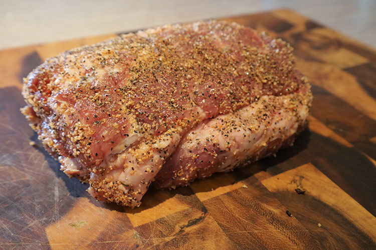 uncooked seasoned beef chuck on a wooden board