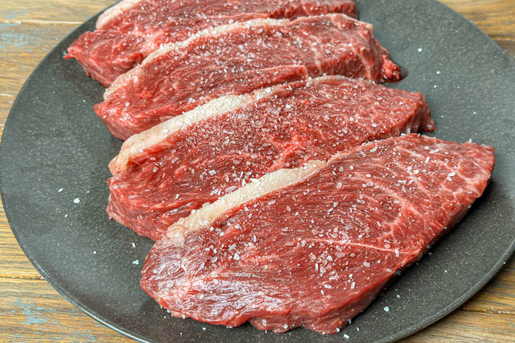 four pieces of salted steak on a plate