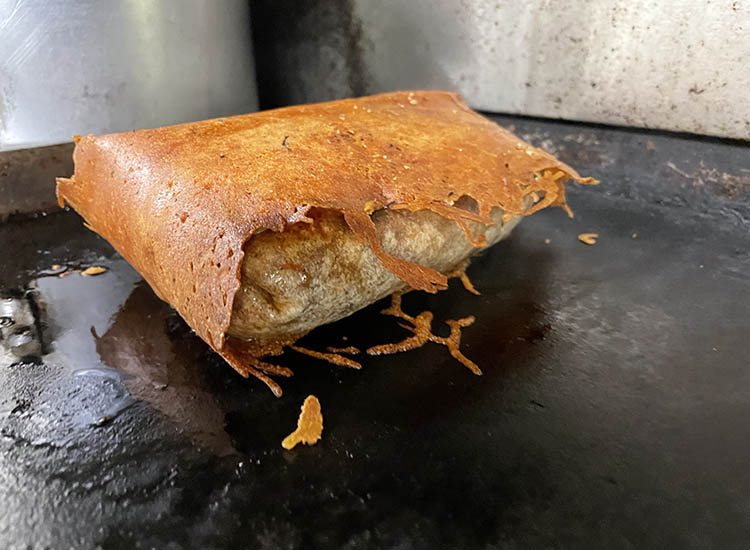 breakfast burrito wrapped in jalapeno cheese blanket on a griddle