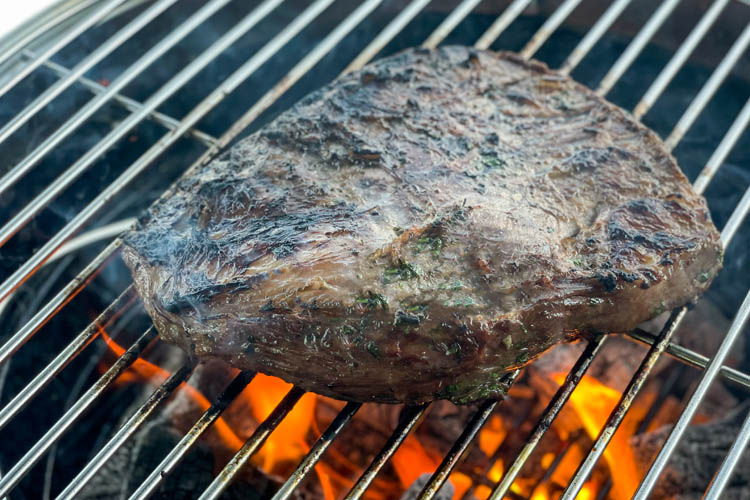 skirt steak on the smoker with flames underneath