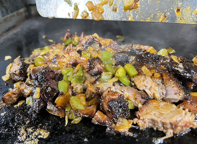 veggies, meat and eggs burrito filling on a griddle