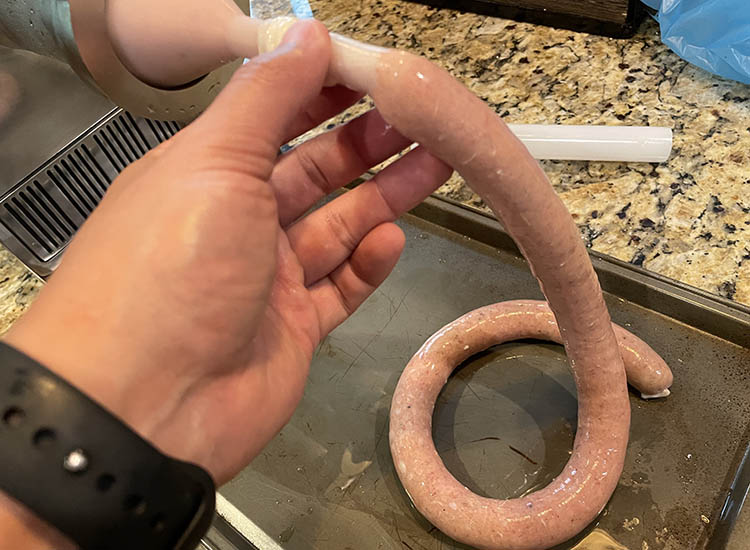 stuffing a hotdog with a stuffing attachment on a meat grinder