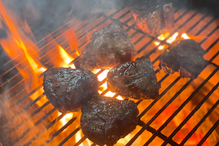 lamb chops on grill with flames coming though grill