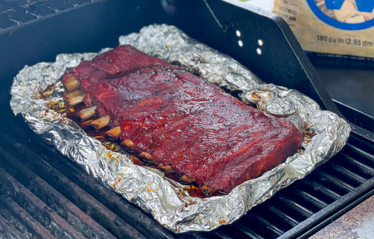rack of ribs smoking on a gas grill