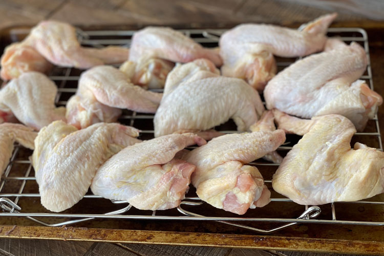 raw wings on a rack over a tray