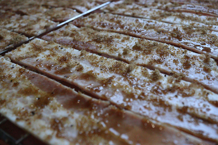 raw bacon with brown sugar sprinkled on, on a rack