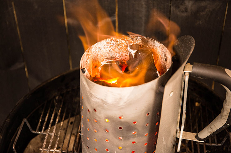 charcoal chimney starter with lit lump charcoal