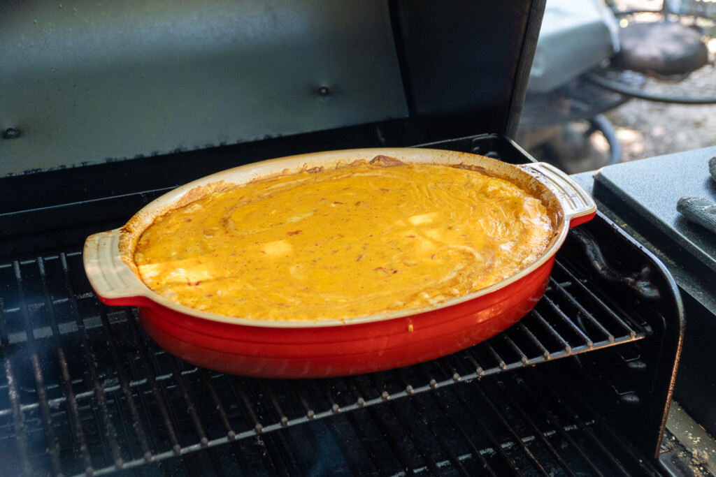 cooked queso dip in a red dish on the smoker