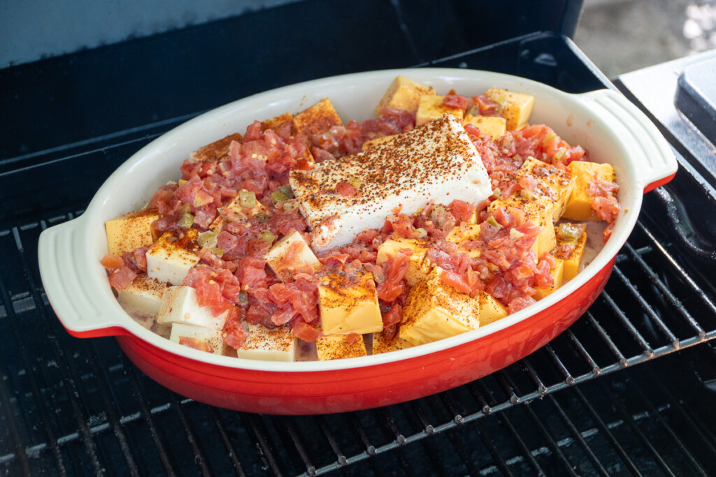 uncooked queso ingredients in a red dish in the smoker