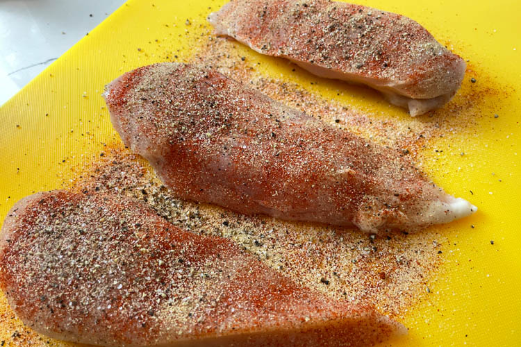 seasoned raw chicken on yellow board
